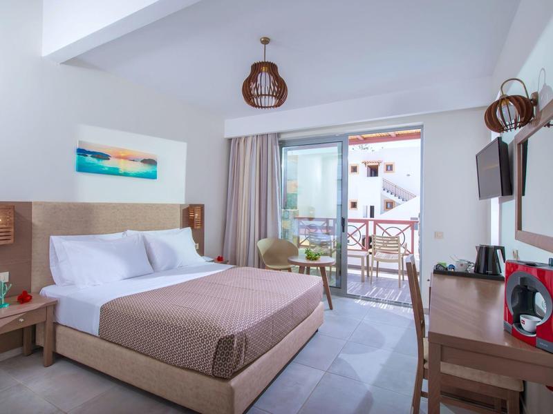 Helles Schlafzimmer mit Doppelbett, Balkon, Fernseher, Holzlampen und moderner Einrichtung.