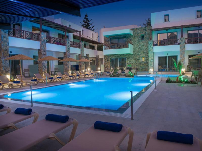 Modernes Hotel mit beleuchtetem Pool und Liegen in gemütlicher, abendlicher Atmosphäre.