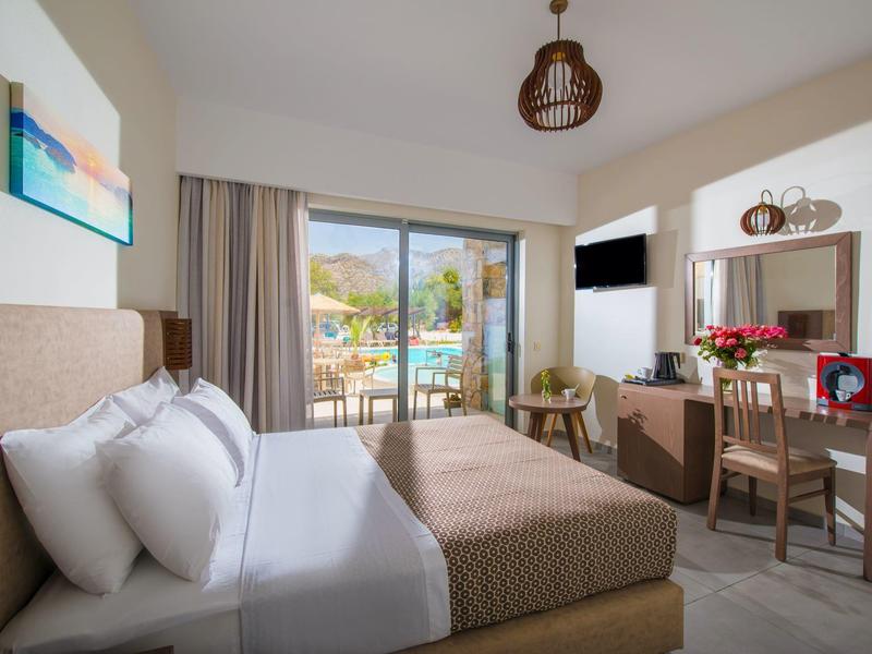 Helles Schlafzimmer mit großem Bett, Balkon mit Bergblick und Schreibtisch mit Blumen.