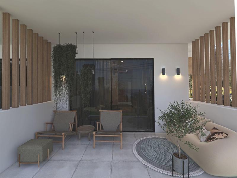 Moderner Außenbereich mit grauen Sitzmöbeln, runden Teppich und grünen Pflanzen vor Glaswand.