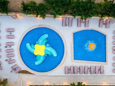 Nowoczesny obszar basenowy z okrągłym i prostokątnym basenem oraz leżakami po bokach.