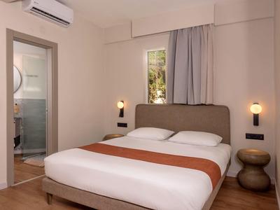 Przytulny pokój hotelowy z łóżkiem podwójnym, dwoma stolikami nocnymi i widokiem na łazienkę.