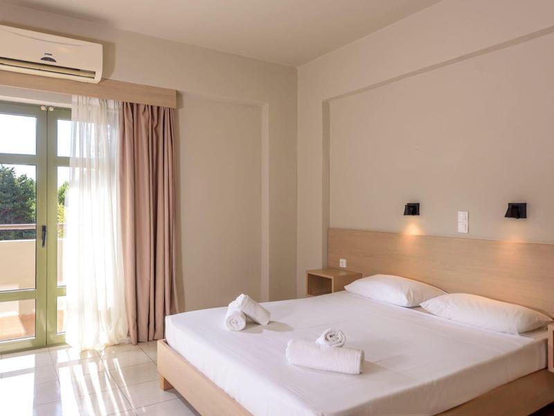 Jasno urządzone sypialnia z podwójnym łóżkiem, balkonem i zasłonami.