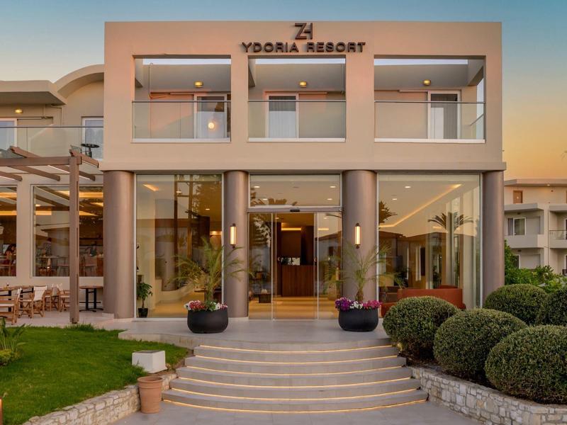 Nowoczesne wejście do ośrodka z szklanymi drzwiami i zadbanym ogrodem o zmierzchu.