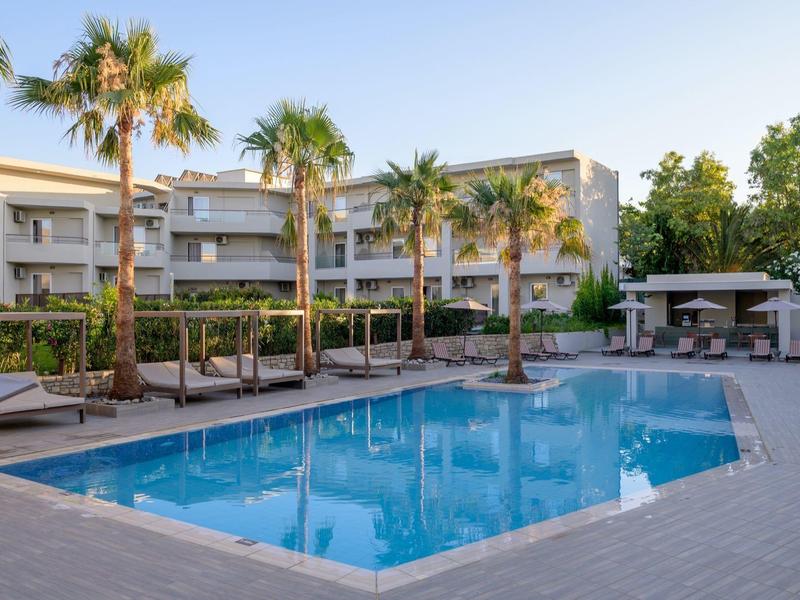 Nowoczesny basen hotelowy z leżakami i palmami o zachodzie słońca.