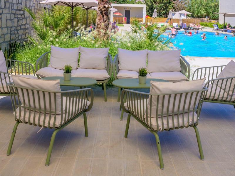 Nowoczesny zewnętrzny kącik z meblami wypoczynkowymi i widokiem na basen.