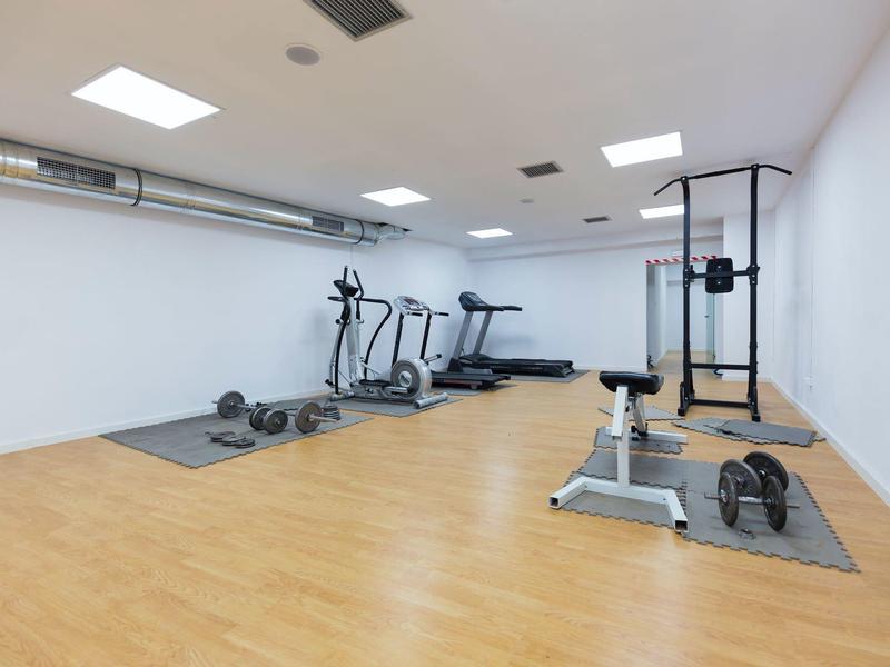 Nowoczesna siłownia z bieżnią, rowerem eliptycznym, ciężarami i sprzętem do ćwiczeń na drewnianej podłodze.