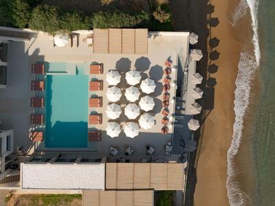 Luchtfoto van een hotel met zwembad, ligstoelen en strand aan zee.