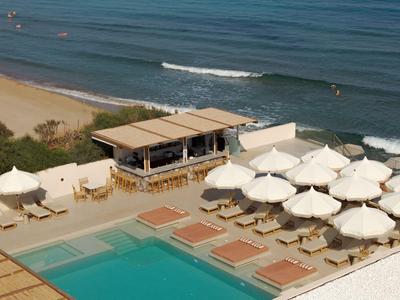 Strandhotel met parasols, ligbedden en uitzicht op zee.