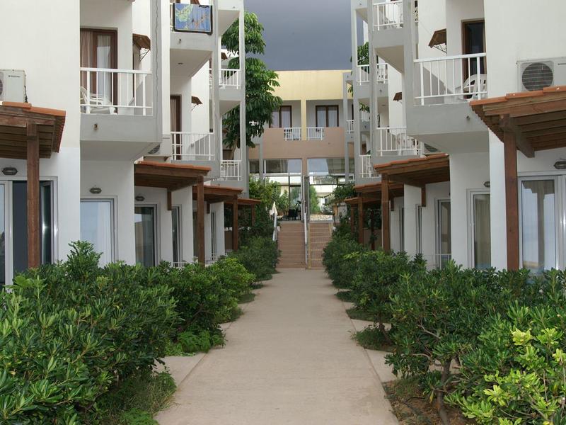 Moderner Innenhof mit hellen Gebäuden, grünem Bewuchs und Weg in der Bildmitte.