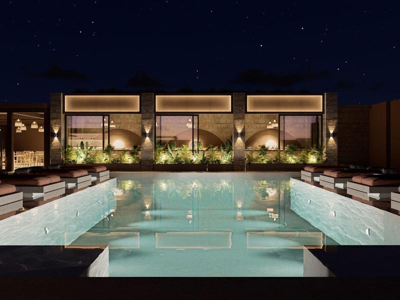 Beleuchtetes Schwimmbecken bei Nacht mit Lounge-Bereichen in einem modernen Hotel.