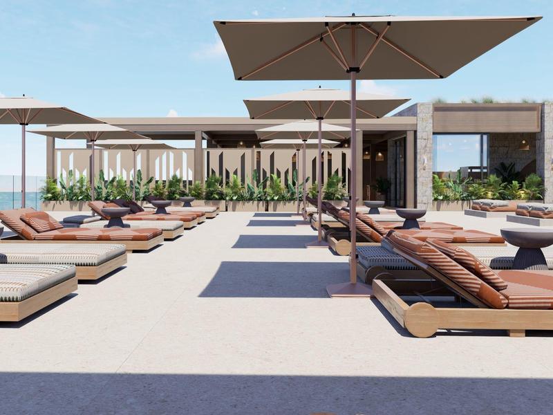 Moderne Hotelterrasse mit Liegen und Sonnenschirmen mit Meerblick bei klarem Himmel.