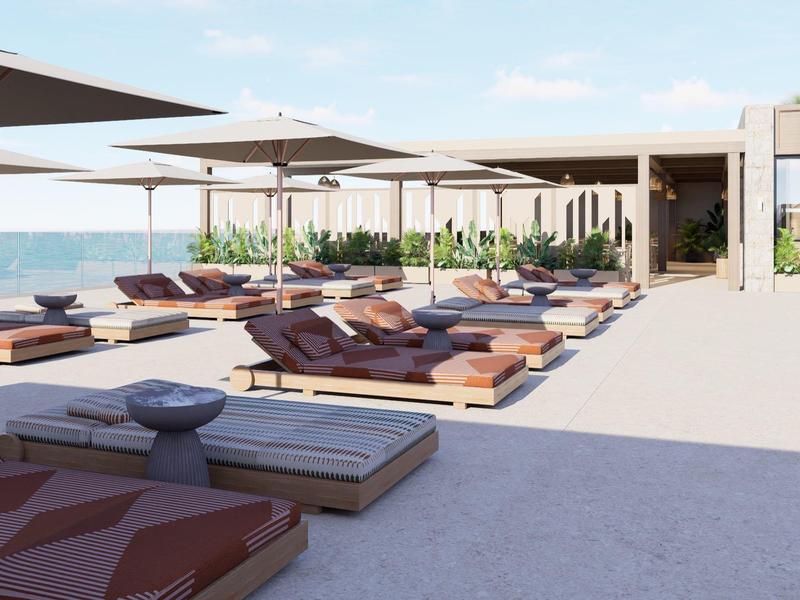 Moderne Dachterrasse mit Liegestühlen und Sonnenschirmen mit Meerblick an einem sonnigen Tag