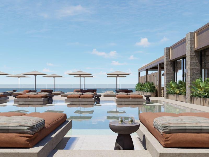 Moderner Hotelpool mit Liegen und Sonnenschirmen mit Blick auf das Meer bei klarem Himmel.