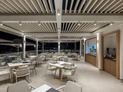 Espace extérieur couvert moderne d'hôtel avec tables dressées et chaises la nuit.