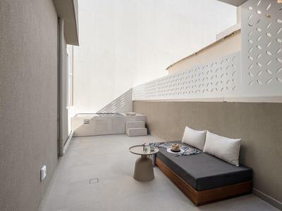 Balcon moderne avec banc rembourré, deux coussins et une petite table d'appoint avec des boissons.