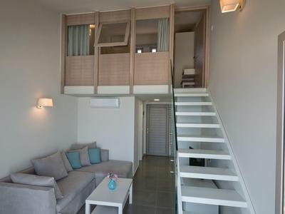 Chambre moderne avec canapé-lit, petit canapé et escalier menant à un lit mezzanine.