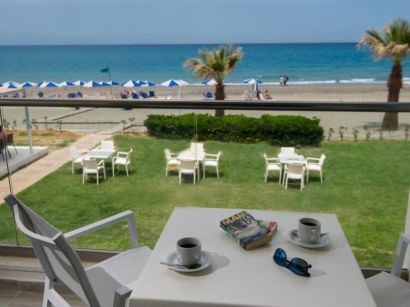 Table de balcon avec tasses face à la mer, plage et chaises longues