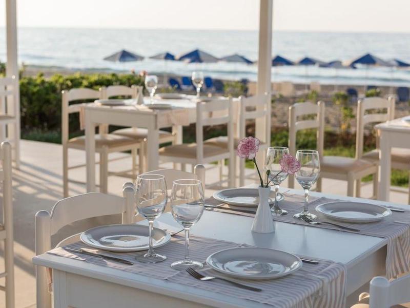 Une table dressée sur une terrasse avec vue sur la plage et la mer en arrière-plan.