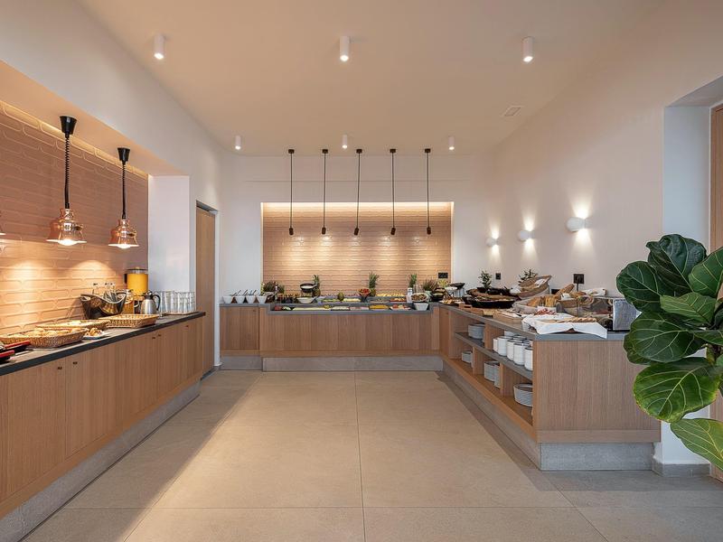 Cuisine d'hôtel moderne avec armoires en bois, comptoirs et éclairages contemporains sous un éclairage de plafond lumineux.