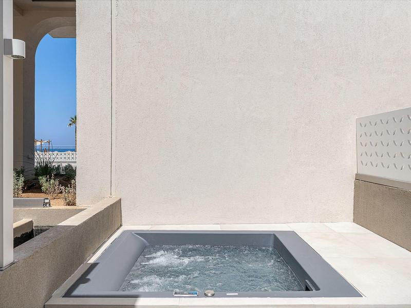 Bain à remous moderne sur une terrasse blanche avec vue sur un ciel bleu.