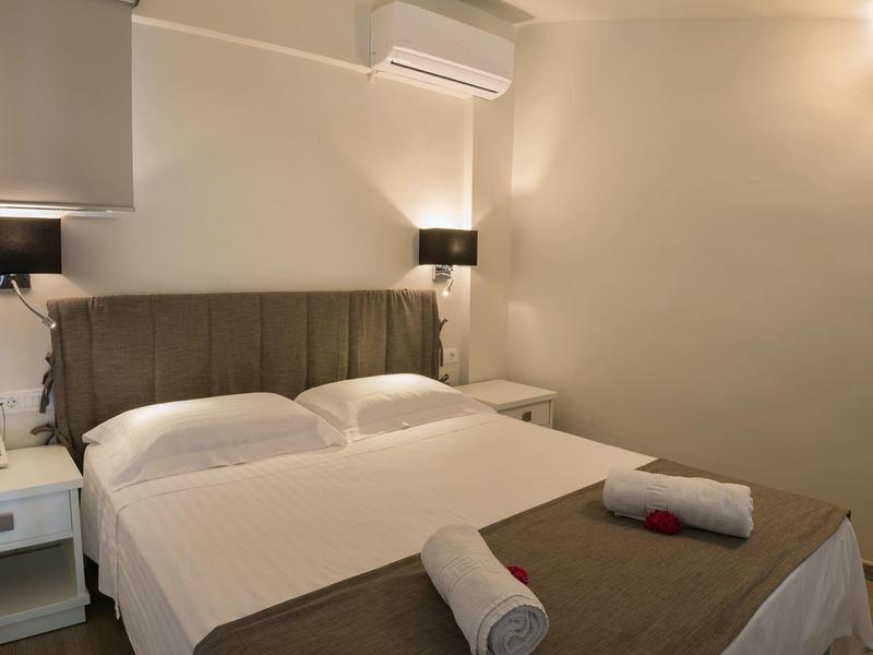 Chambre moderne avec lit double, tables de nuit blanches et lampes murales chaudes.