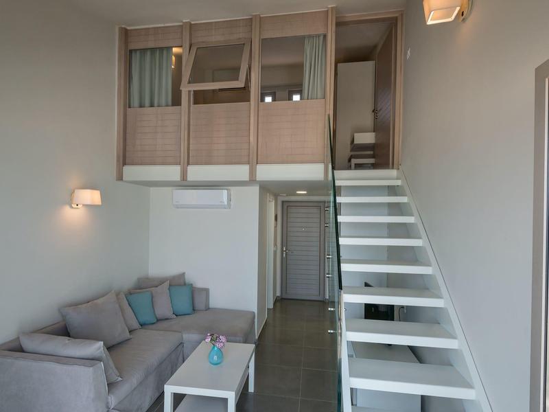 Chambre moderne avec canapé-lit, petit canapé et escalier menant à un lit mezzanine.