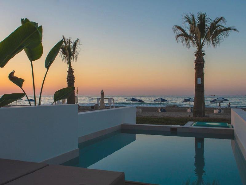 Piscine moderne avec palmiers et vue sur la mer au coucher du soleil