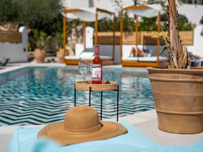 Área de piscina relajante con sombrero de sol y bebida en una mesa pequeña junto a la tumbona