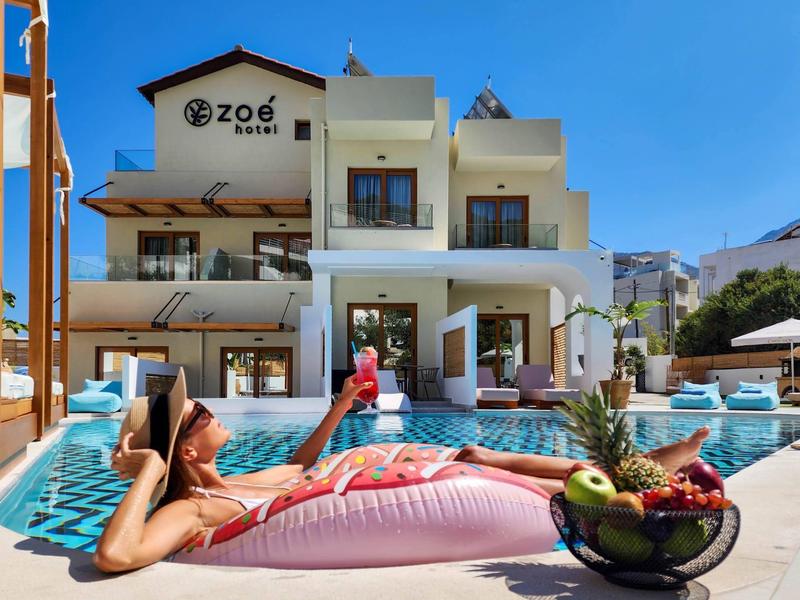 Vrouw ontspant op een drijver in het zwembad voor een modern hotel bij zonnig weer.