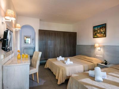 Helles Hotelzimmer mit zwei Einzelbetten, Schreibtisch, Stuhl, Wandfernseher und großem Kleiderschrank.