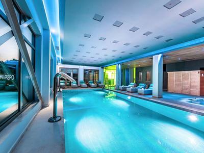 Moderner Innenpool mit Beleuchtung, Liegestühlen und glatten, hellen Wänden in kühlem Blau.