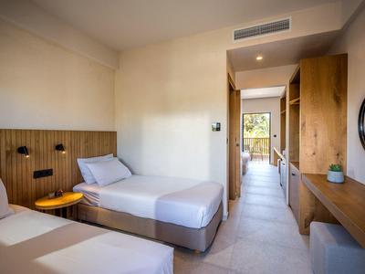 Modernes Hotelzimmer mit zwei Einzelbetten, Holzmöbeln und hellem Fliesenboden.