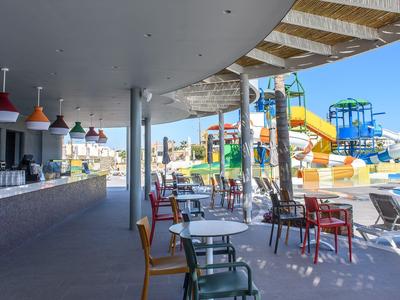 Espace ouvert avec des sièges dans un parc de toboggans aquatiques à côté d'un bar avec des chaises et tables colorées.