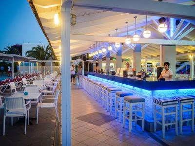 Espace bar d'un hôtel avec éclairage moderne et sièges extérieurs en soirée.