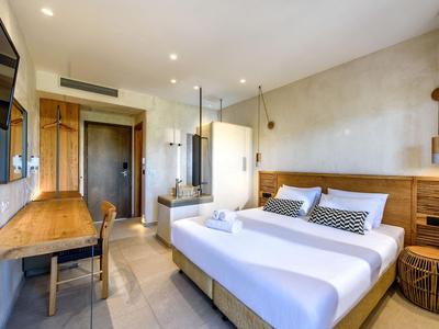 Chambre d'hôtel moderne avec lit double, détails en bois et bureau aux tons neutres.