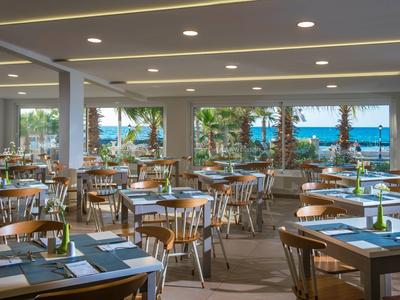Restaurant spacieux avec des tables en bois et vue sur la mer.