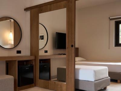 Chambre d'hôtel avec deux lits simples, grand miroir et une petite télévision fixée au mur.