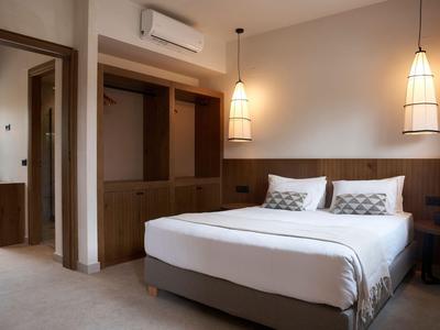 Chambre d'hôtel moderne avec lit blanc et lumière chaude des lampes suspendues.