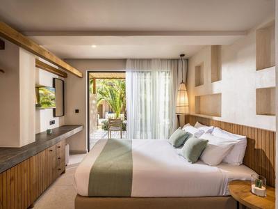 Chambre d'hôtel moderne avec lit double, détails en bois et terrasse avec vue sur des palmiers.