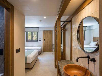 Couloir d'hôtel moderne avec salle de bain, éléments en bois et vue sur une chambre lumineuse avec lit double.