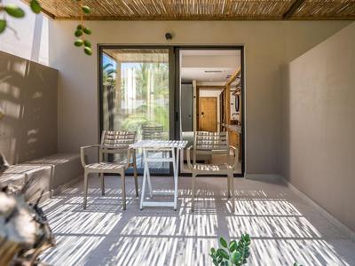 Balcon d'hôtel moderne avec mobilier en verre et métal, lumière naturelle et toit ombragé.