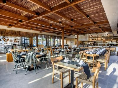 Restaurant lumineux et spacieux avec plafond à poutres en bois et sièges modernes et confortables.