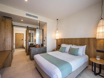 Chambre d'hôtel moderne avec lit double, accents en bois et éclairage chaleureux.