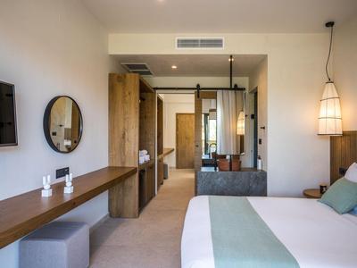 Chambre d'hôtel moderne avec grand lit, bureau, miroir et éclairage d'ambiance.
