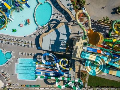 Vue aérienne d'un parc d'attractions avec bassins d'eau, toboggans et attractions colorées.
