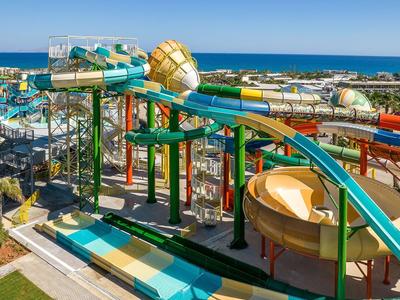 Grand parc aquatique avec des toboggans colorés et vue sur la mer en arrière-plan.