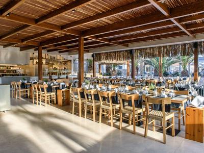 Großes, offenes Restaurant mit Holzbalkendecke, langen Holztischen und vielen Stühlen.