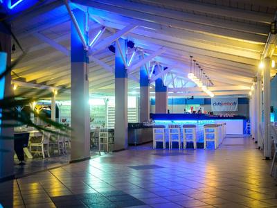 Moderner Innenraum mit blauer Beleuchtung, Barbereich und Fliesenboden unter Holzdecke.