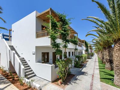Hôtel moderne avec bâtiments blancs, balcons et palmiers le long du trottoir.